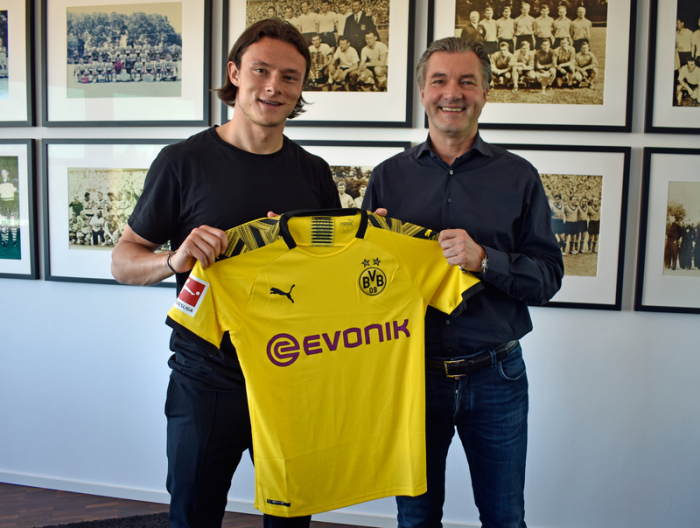 Neuzugang Nico Schulz zusammen mit Michael Zorc (r), Sportdirektor des Fußball-Bundesligisten Borussia Dortmund, ein Trikot hochhaltend. Foto: BVB/Borussia Dortmund/dpa
