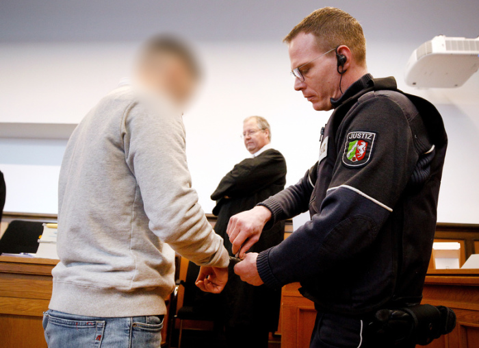 Dem Hauptangeklagten (l) werden von einem Justizbeamten die Handschellen abgenommen, in der Mitte steht sein Anwalt Thilo Pforte. Foto: Roland Weihrauch/Dpa