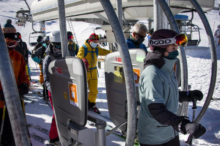 Skifahrer mit Gesichtsmasken stehen am Eröffnungstag des Skigebiets Verbier in den Schweizer Alpen in der Schlange für den Sessellift. Foto: epa/Jean-christophe Bott