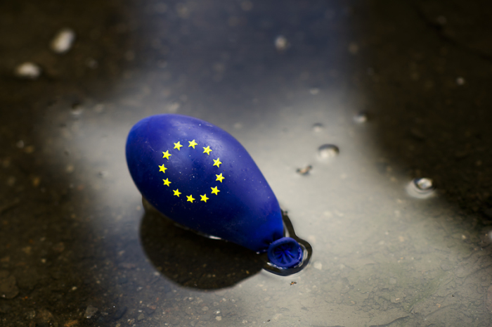 Ein fast leerer Luftballon mit dem Zeichen der Europäischen Union (EU) liegt in einer Pfütze. Angesichts zunehmender internationaler Spannungen stehen Europas Wirtschaft schwierige Zeiten bevor. Foto: Arno Burgi/Dpa-zentralbild/dpa