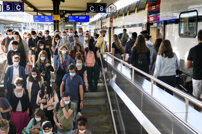 Passagiere mit Gesichtsmasken gehen in einem Bahnhof in Lausanne zu Fuß. Foto: epa/Laurent Gillieron