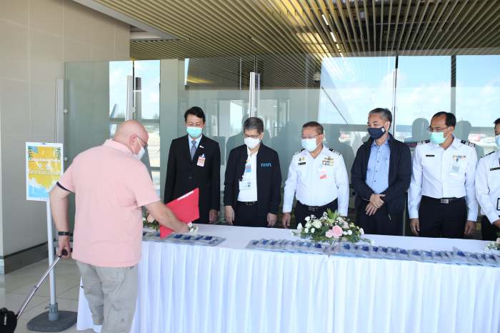 Einer der ersten ausländischen Besucher wird von führenden Mitarbeitern des Flughafens und von Beamten der Tourismusbehörde bei seiner Ankunft am Phuket International Airport begrüßt. Foto: Tourism Authority Of Thailand