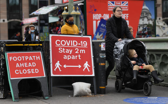 Fußgänger passieren ein Covid-19-Schild in Westminster, London. Foto: epa/Andy Rain