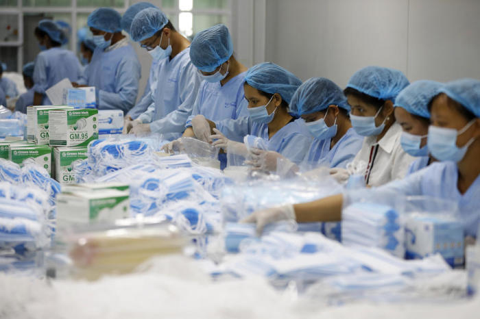 Arbeiter an einer Produktionslinie für medizinische Gesichtsmasken in der 