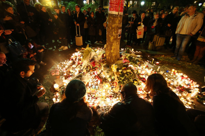 Trauernde Menschen zünden am 16.11.2015 vor dem Konzertsaal «Bataclan» in Paris Kerzen an und legen Blumen nieder. Rund sechs Jahre nach der Anschlagsnacht des 13. November 2015. Foto: alliance/dpa