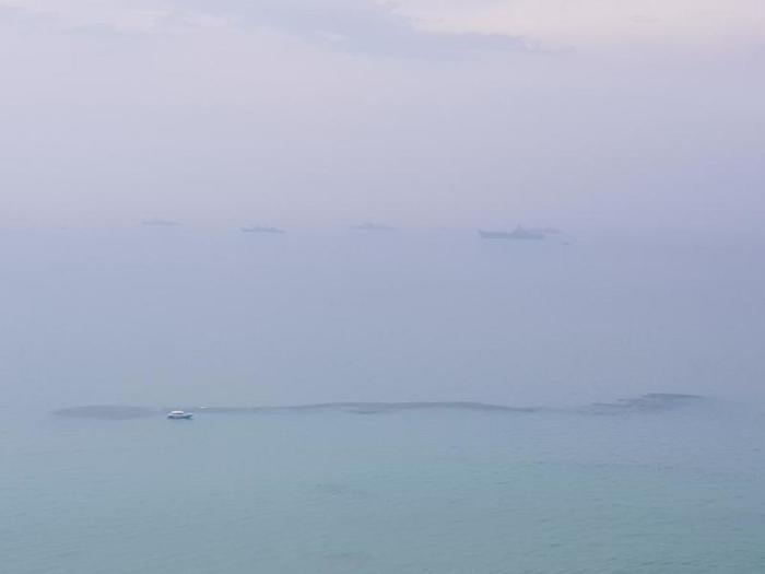 Im Vordergrund die schwarzen Flecken, am Horizont die vor Anker liegenden Marineschiffe. Foto: Jahner