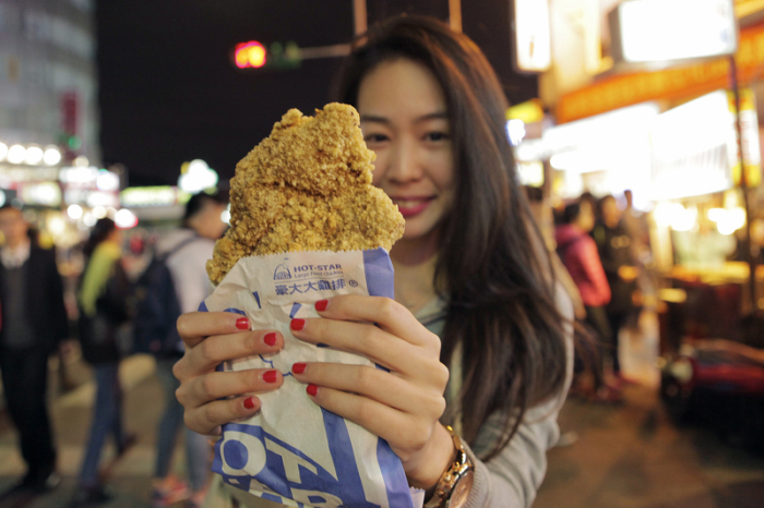 Knuspriger Snack: Eine Besucherin des Shilin Night Market in Taipeh hat sich frittiertes Hähnchen gekauft. Foto: Taiwan Tourism Bureau/dpa-tmn