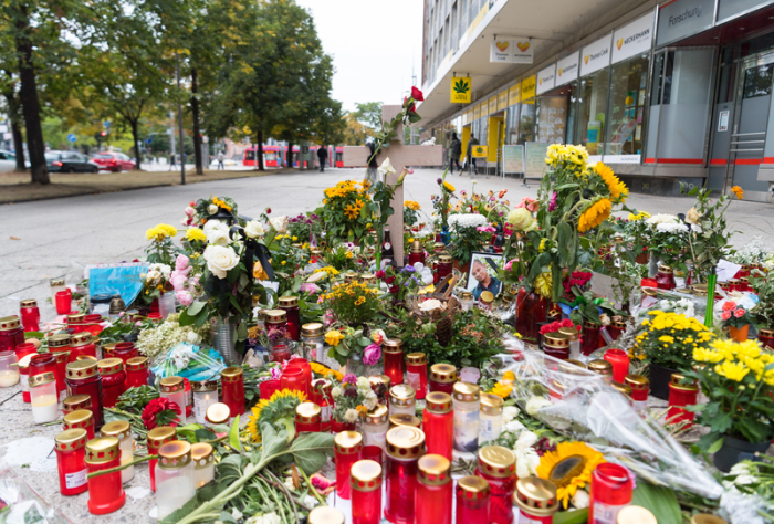 Ein Holzkreuz und ein Foto des Opfers stehen zwischen zahlreichen Blumen und Kerzen am Tatort. Foto: Monika Skolimowska/Zb/dpa