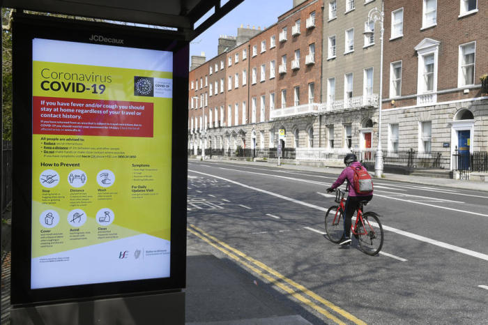 Eine Radfahrerin fährt an einer Bushaltestelle mit einer Gesundheitswarnung auf der Covid-19 in Dublin vorbei. Foto: epa/Aidan Crawley