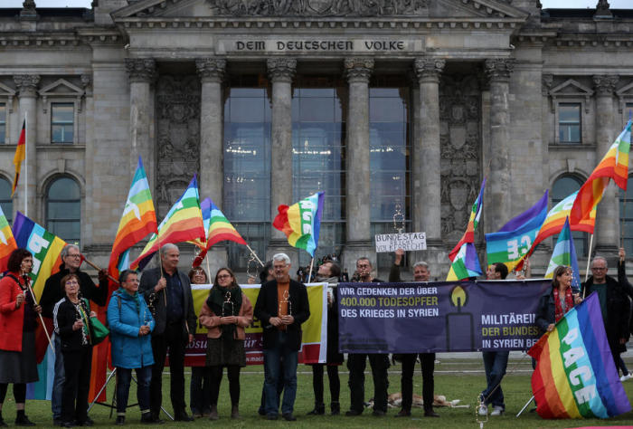 Menschen halten Plakate während einer Kundgebung gegen eine Ausweitung des Bundeswehreinsatzes in Syrien und im Irak in Berlin. Foto: epa/Felipe Trueba