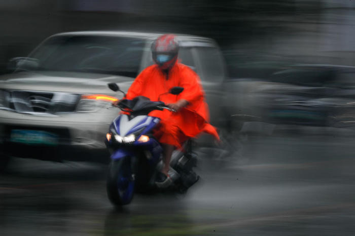 Der Motorradfahrer trägt einen Regenmantel während eines Regengusses in Pasig City. Foto: epa/Mark R. Cristino