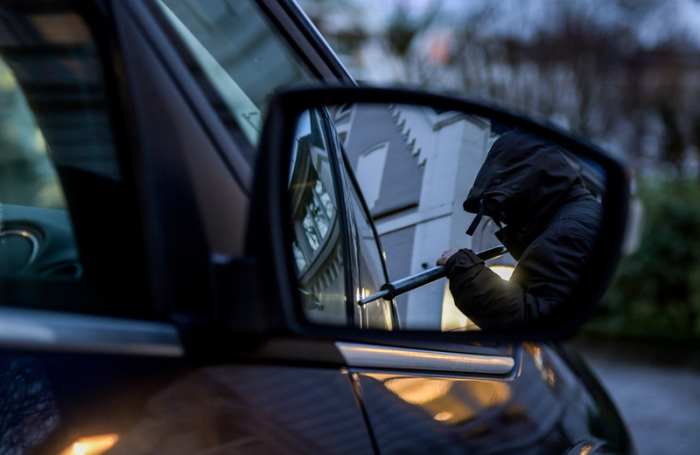 Ein Mann versucht eine Autotür mit einer Metallstange aufzubrechen (gestellte Szene). Autodiebe haben im vergangenen Jahr deutlich seltener zugeschlagen, dafür wird ihre Beute immer wertvoller. Foto: Axel Heimken/Dpa