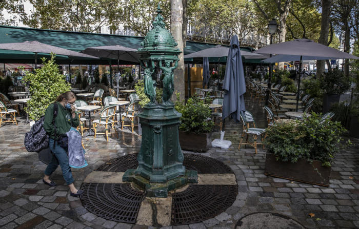 Ein Passant, der eine Gesichtsmaske trägt, geht zur Mittagszeit an einer verlassenen Bistroterrasse im lateinischen Viertel im Zentrum von Paris vorbei. Foto: epa/Ian Langsdon