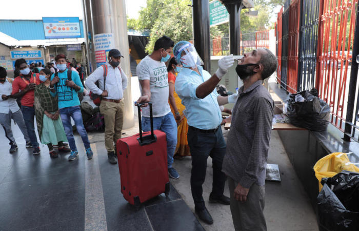 Indische Passagiere unterziehen sich an einem Bahnhof in Neu-Delhi einem COVID-19-Abstrich-Test. Foto: epa/Rajat Gupta