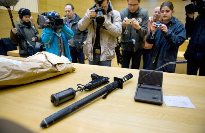 Fotografen fotografieren eine Schusswaffe und einen Schlagstock in einem Gerichtssaal des Landgerichts Bielefeld. Foto: epa/Bernd Thissen