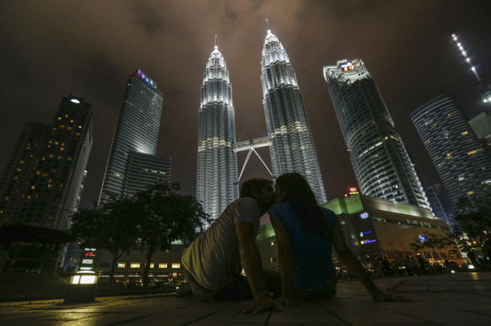 Ein Pärchen küsst sich vor den Petronas Twin Towers in Kuala Lumpur. Foto: epa/Fazry Ismail