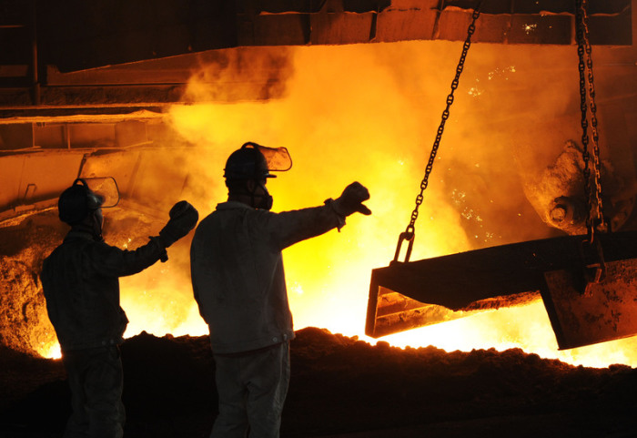 Stahlarbeiter in Schutzkleidung arbeiten vor einem angestochenen Hochofen in dem staatlichen Unternehmen «Dongbei Special Steel». Foto: Liu Debin/Sipa Asia Via Zuma Wire/dpa