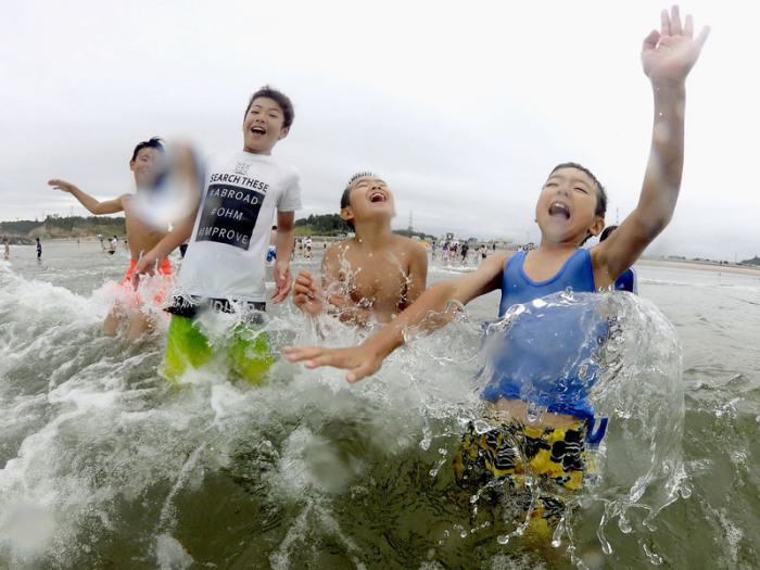 Kinder spielen im Wasser am Strand. Nach der Nuklearkatastrophe von Fukushima wurde der Strand zum ersten Mal wieder für Besucher zugelassen. Foto: --/Kyodo/dpa 