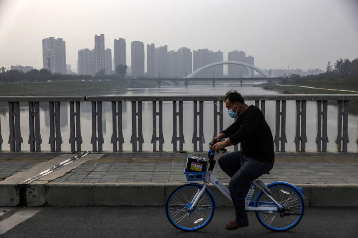 ein Mann mit Gesichtsmaske beim Fahrradfahren auf einer Brücke während eines verschmutzten Tages in Peking. Foto: epa/Wu Hong