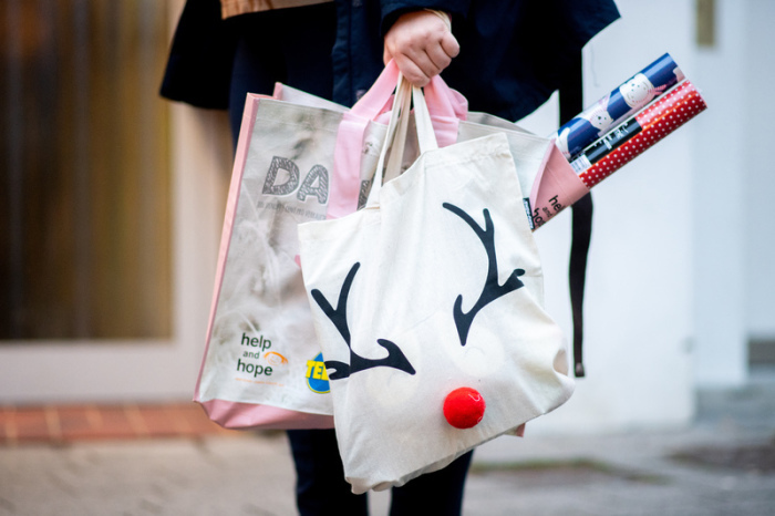 Eine junge Frau geht am frühen Abend mit einer weihnachtlichen Einkaufstasche durch die Innenstadt. Dem Weihnachtsgeschäft in den niedersächsischen Innenstädten droht auch in diesem Jahr eine schwere Corona-... Foto: Hauke-Christian Dittrich/dpa