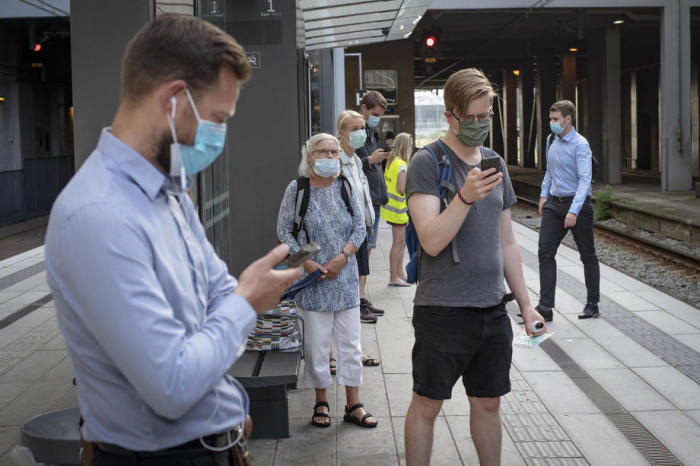 Die Fahrgäste tragen Masken, während sie auf eine Straßenbahn in Aarhus warten. Foto: epa/Bo Amstrup