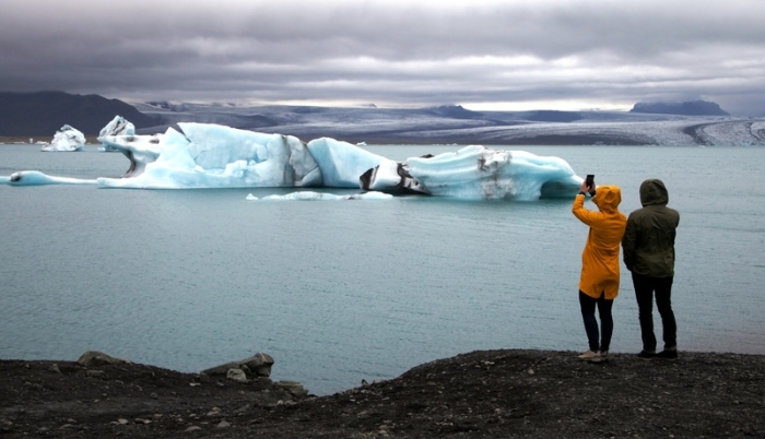 Touristen machen an der südisländischen Gletscherlagune Jökulsárlón Fotos vom See und den darin schwimmenden Eisbergen. Foto: Steffen Trumpf/Dpa