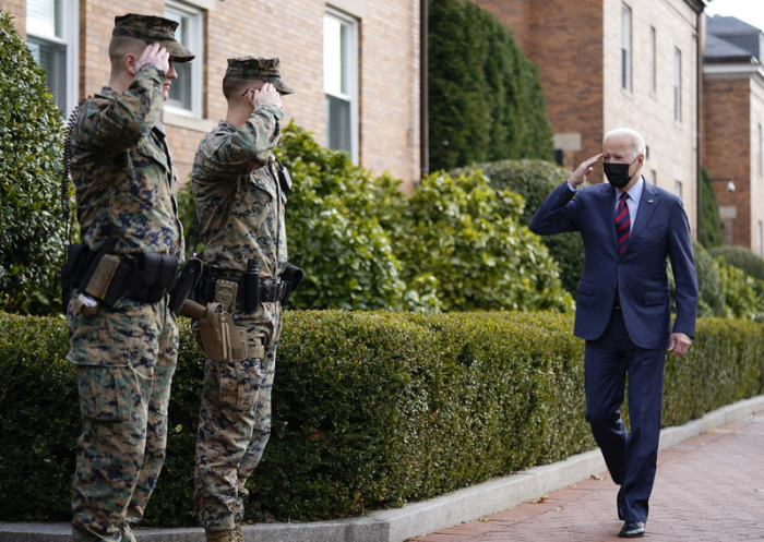 Joe Biden (r), Präsident der USA, grüßt Soldaten, während er an einer Marinekaserne vorübergeht. Foto: Andrew Harnik