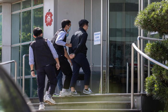Der Apple Daily-Chefredakteur Ryan Law (R) wird von der Polizei zum Büro von Next Media, dem Herausgeber von Apple Daily, in Hongkong eskortiert. Foto: epa/Jerome Favre