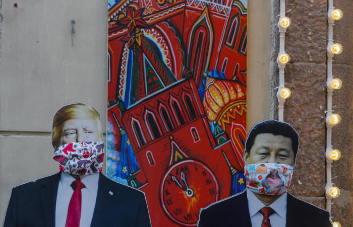Pappfiguren des chinesischen Präsidenten Xi Jinping (R) und des US-Präsidenten Donald Trump (L) mit Gesichtsmasken. Foto: epa/Sergei Ilnitsky