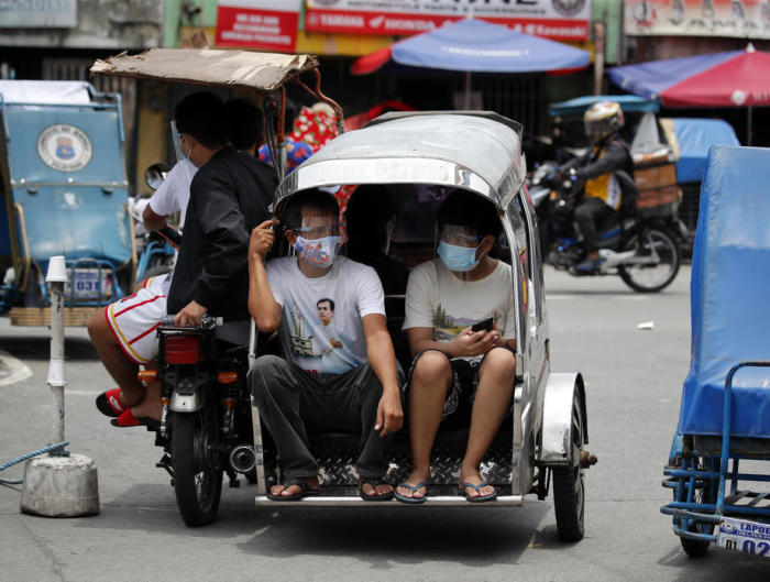 Filipinos mit Gesichtsmasken fahren in Manila, Philippinen, auf einem dreirädrigen Motorrad. Foto: epa/Francis R. Malasig