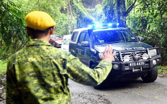 Ein Sicherheitsbeamter gibt einem ankommenden Einsatzwagen bei der Such- und Rettungsaktion für die vermisste Nora in einem Wald Handzeichen. Foto: Dusa Abas/Bernama/dpa