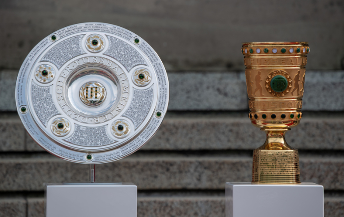 Die Meisterschale und der DFB-Pokal stehen während des Empfangs der Mannschaft des FC Bayern München nebeneinander im Hofgarten hinter der bayerischen Staatskanzlei. Foto: Peter Kneffel/Dpa