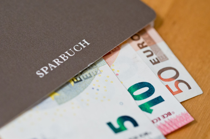 Geldscheine (Euro) liegen in einem Sparbuch. Bayerns Ministerpräsident Söder will Strafzinsen für Kleinsparer gesetzlich verbieten lassen. Foto: Daniel Karmann/Dpa
