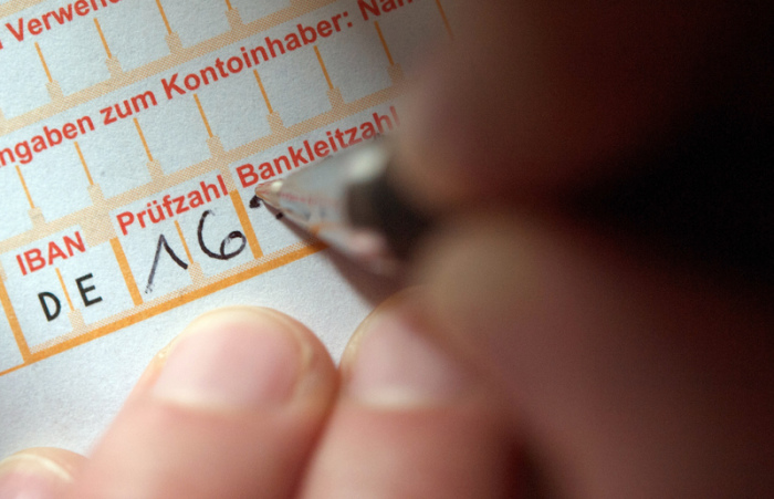 Eine Frau füllt ein Überweisungsformular aus. In der Zinsflaute sind Banken und Sparkassen erfinderisch geworden. Foto: Marijan Murat/Dpa