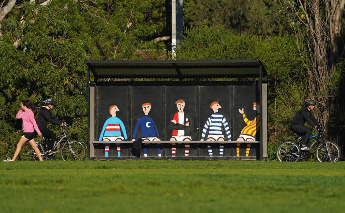 Leute trainieren in der Nähe einer leeren Spielerbank auf einem Fußballplatz in Melbourne. Foto: epa/Scott Barbour