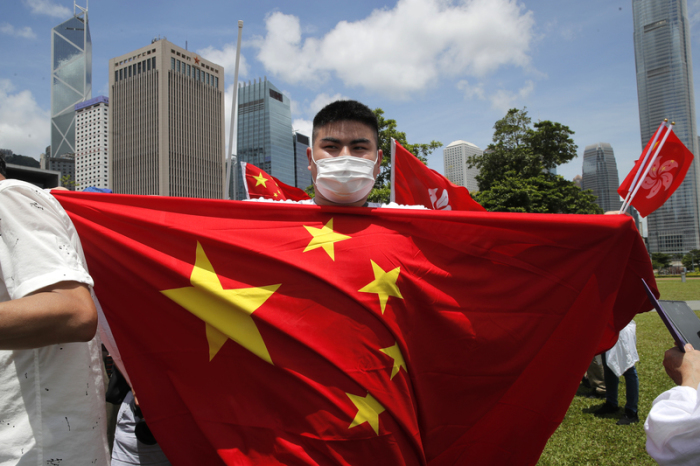 Ein China-Anhänger hält eine chinesische Nationalflagge während einer Kundgebung zur Feier der Verabschiedung eines nationalen Sicherheitsgesetzes für Hongkong vor seinen Körper. Ungeachtet weltweiter Kritik hat China n... Foto: Kin Cheung/Ap/dpa