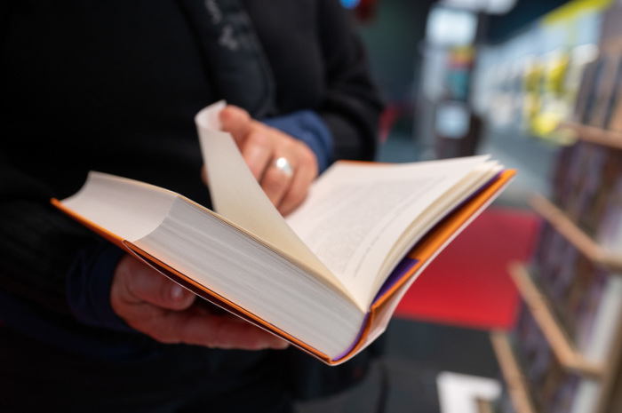 Eine Frau blättert in einem Buch am zweiten Tag für Fachbesucher auf der Frankfurter Buchmesse 2021. Die Buchmesse 2021 findet vom 20. bis 24. Oktober statt. Foto: Sebastian Gollnow/dpa