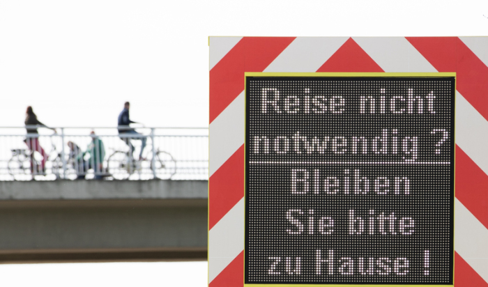 «Reise nicht notwendig? Bleiben Sie bitte zu Hause» steht auf einer mobilen Infotafel auf der Autobahn 30 am Grenzübergang zwischen Deutschland und den Niederlanden. Foto: Friso Gentsch/dpa