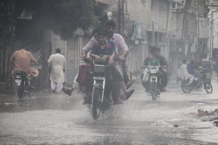 Nach den Monsunregenfällen in Karatschi bahnen sich die Menschen ihren Weg durch eine überflutete Straße. Foto: epa/Nadeem Kahwer