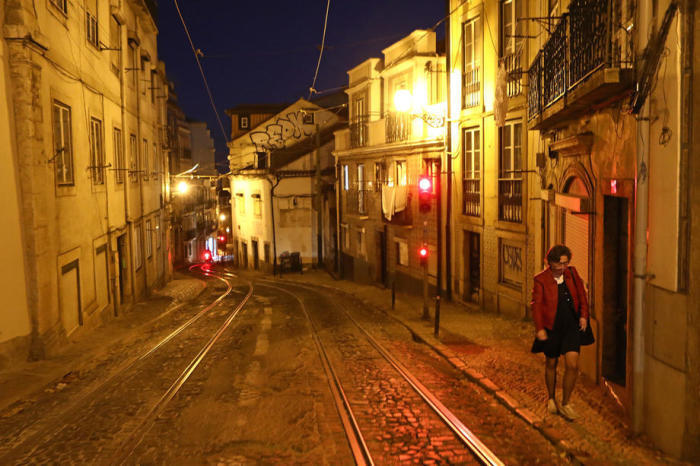 Ein Frau geht in einer verlassenen Straße während der Abriegelung des Ausnahmezustands, als Teil der Maßnahmen zur Eindämmung von Covid-19, in Lissabon. Foto: epa/Antonio Pedro Santos