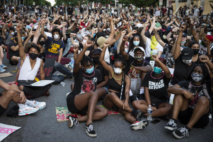 Die Menschen sitzen und erheben ihre Faust aus Protest in der Nähe des Weißen Hauses, wo seit einer Woche Proteste gegen den Tod von George Floyd, der in Polizeigewahrsam starb, stattfinden. Foto: epa/Sarah Silbiger