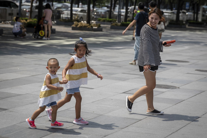 Eine Frau und zwei Kinder gehen im Sanlitun-Viertel von Peking spazieren. Foto: epa/Roman Pilipey
