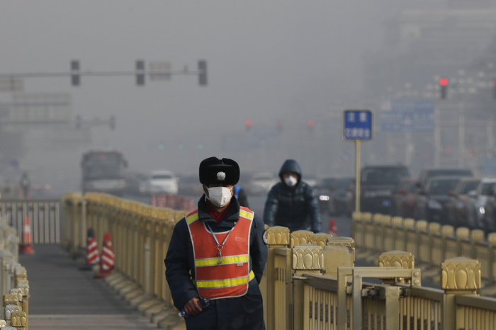 Verkehrspolizist mit Maske geht in der Nähe des Tian_anmen-Platzes während dichter Smog die Sicht trübt und Gesundheit schädigt. Foto: Andy Wong/Ap/dpa