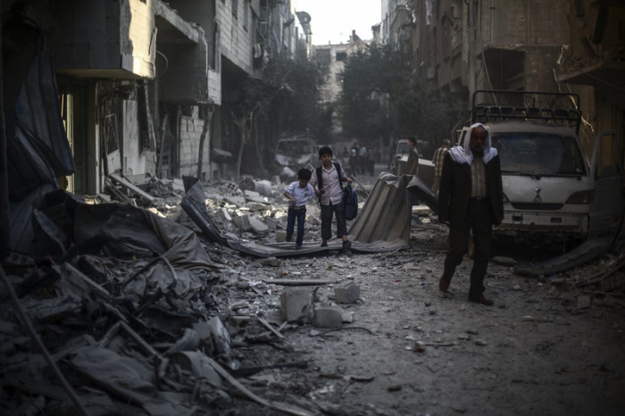 Syrische Jungen gehen zwischen den Trümmern von Gebäuden, die nach einem Luftangriff zerstört wurden. Foto: epa/Mohammed Badra