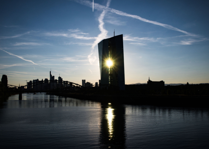 Die untergehende Sonne scheint zwischen den zwei Gebäudeteilen der Zentrale der Europäischen Zentralbank (EZB) hindurch. Foto: Frank Rumpenhorst/Dpa