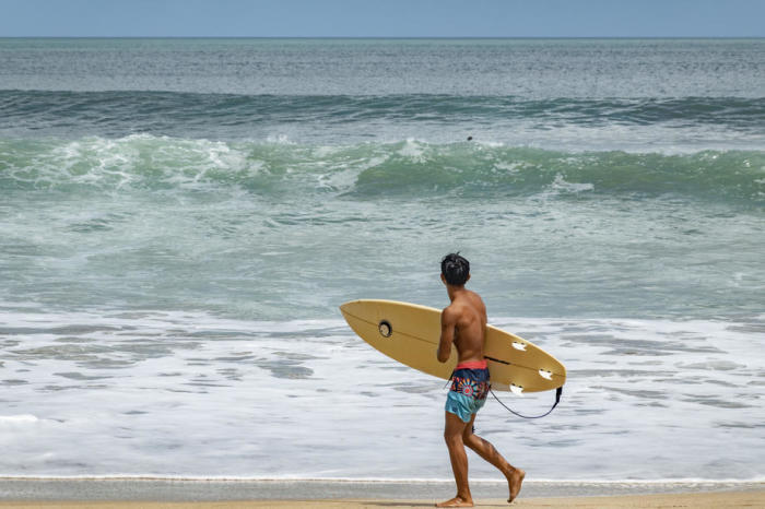 Tourist bereitet sich an einem Strand in Seminyak, Bali, auf das Surfen vor. Foto: epa/Made Nagi