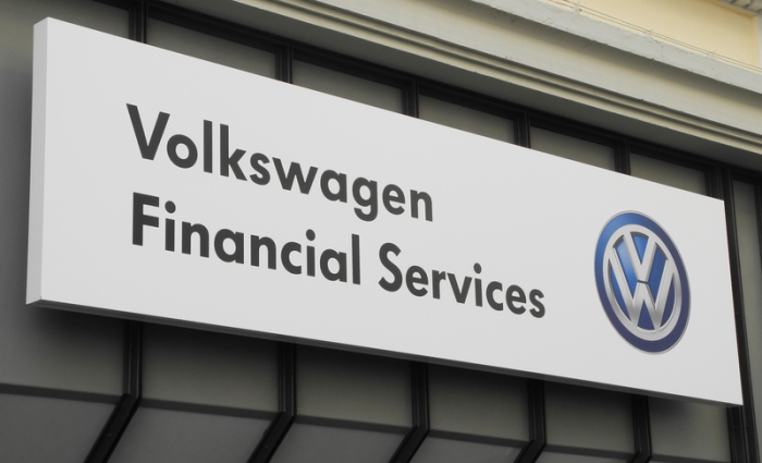 Das Hinweisschild auf eine Filiale des Volkswagen Financial Services hängt an einer Hausfassade. Foto: picture alliance / Dpa