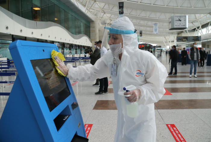 Ein Arbeitnehmer mit Gesichtsmaske und Schutzanzug desinfiziert eine Abfertigungsmaschine nach der Wiederaufnahme von Inlandsflügen im Flughafen Esenboga. Foto: epa/Str