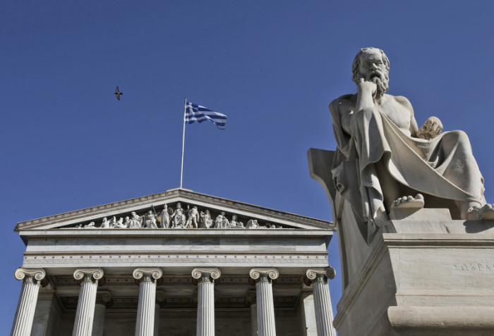 Eine griechische Flagge flattert hinter einer Statue des alten Philosophen Socrates an der Athen-Akademie. Foto: epa/Yannis Kolesidis