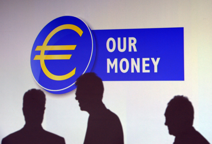 Die Schatten dreier Männer sind in der Zentrale der Europäischen Zentralbank (EZB) auf einer Videowand unter dem Schriftzug «Our Money» zu sehen. Foto: Arne Dedert/Dpa